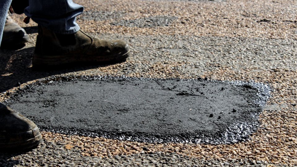 Newly placed asphalt patch filling a repaired section of worn pavement