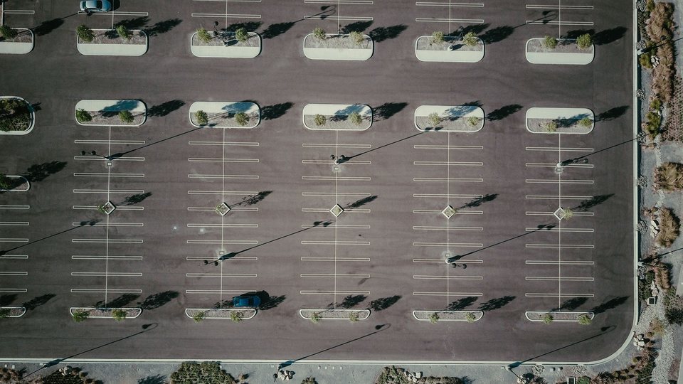 Overhead view of a striped asphalt parking lot with landscaped islands